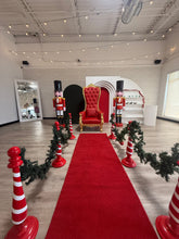 Load image into Gallery viewer, Decorative room with a red carpet, santa throne chair, nutcrackers, and Christmas decorations.