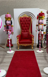 Red throne chair with gold accents in a room decorated with nutcrackers and a red carpet.